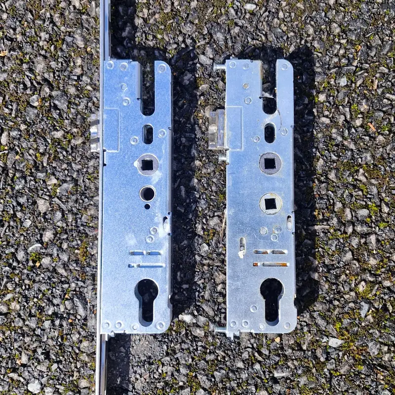 Two uPVC multipoint lock gearboxes laid side by side during a lock repair in Sale