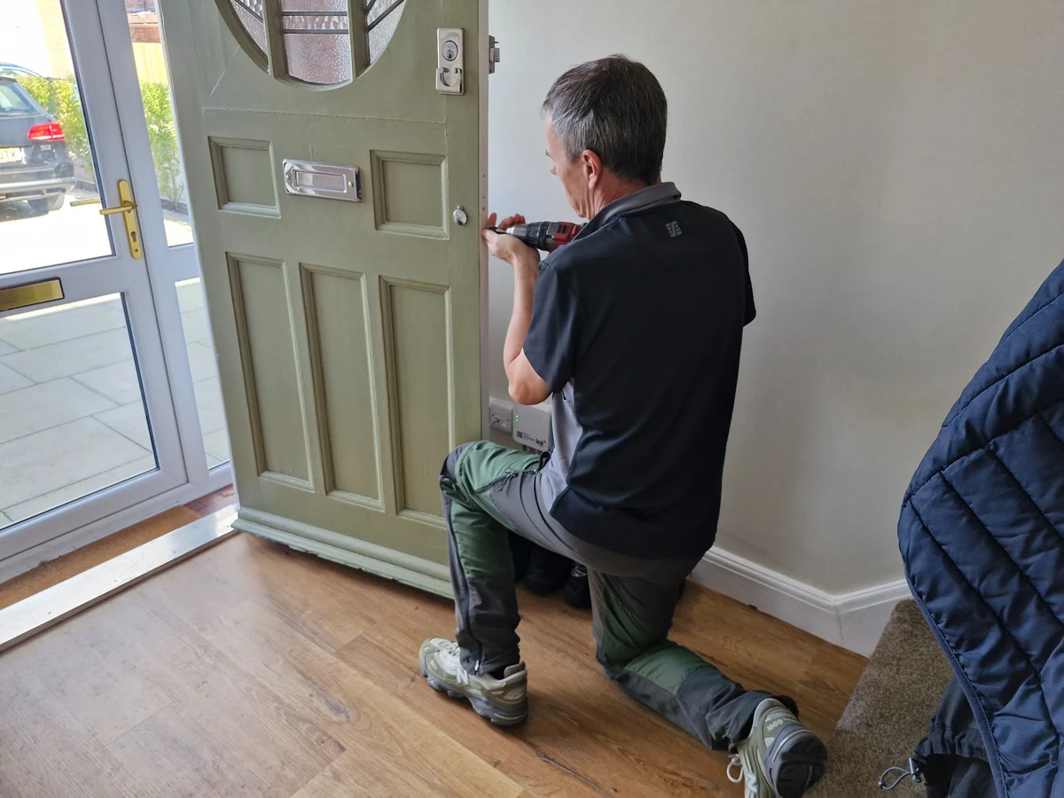 James fitting a lock to a painted wooden front door in Sale